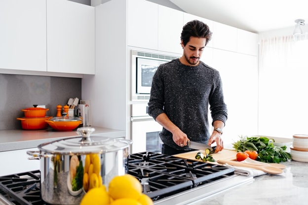 A man cutting vegetables in his kitchen