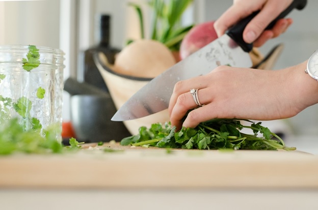 A woman chopping cilantro using a sharp kitchen knife